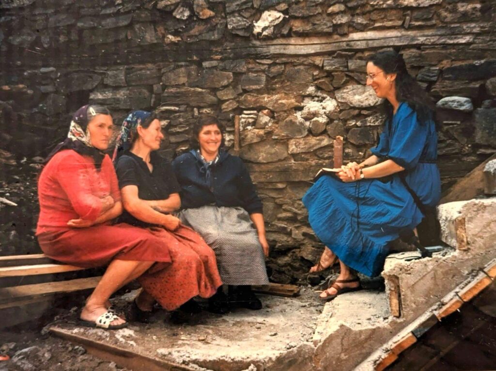 Four women sit on stone steps talking to each other